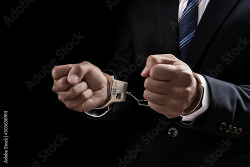 A man in a blue business suit holding hands in handcuffs