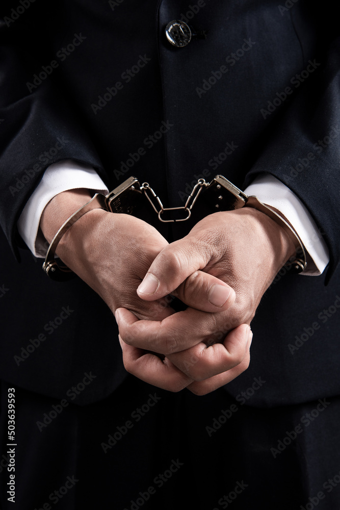 Arrested business man handcuffed hands on the black.