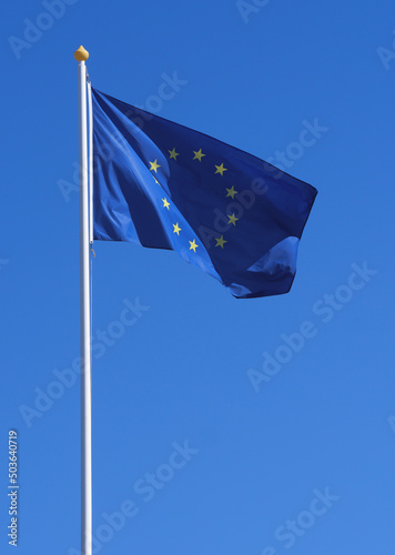 Flag of European Union on a flagpole at sky background. The waving  flag for your political concept about european integration and economic cooperation in Europe.
