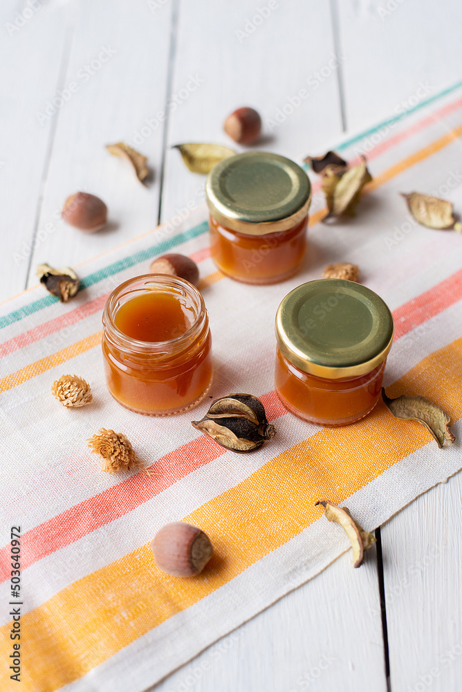jam in several jars on a striped light-colored fabric decorated with dry leaves jam in several jars on a striped light-colored fabric decorated with dry leaves