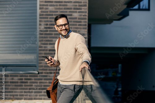 A happy urban man uses a phone outside.