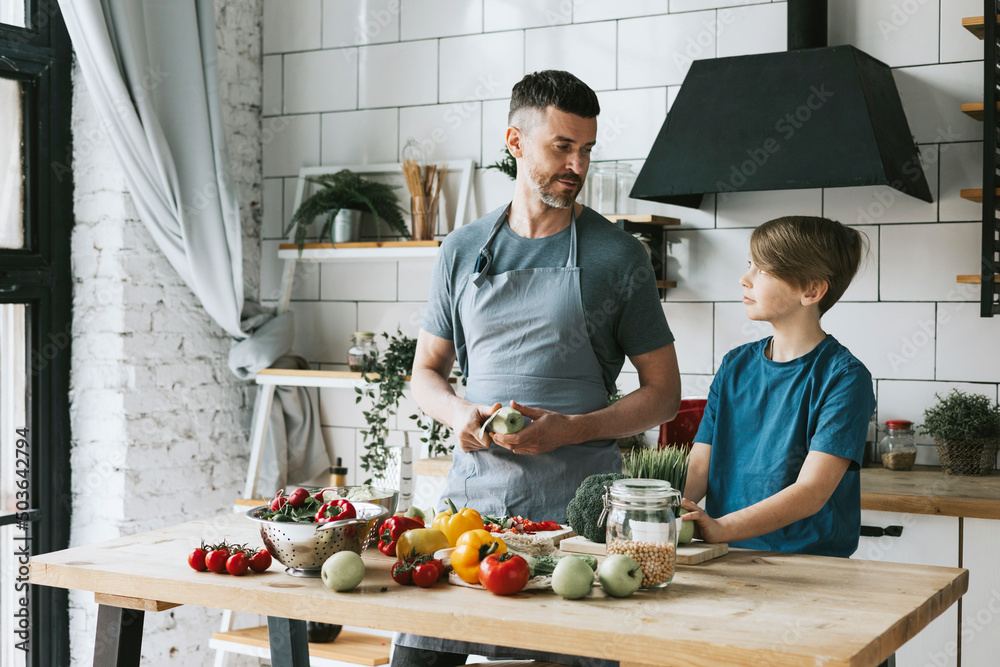 family dad young man and son teenage boy cook vegetable salad in kitchen and spend quality time together, father and son talking and cooking vegetarian food and doing chores, 8 march and mothers day