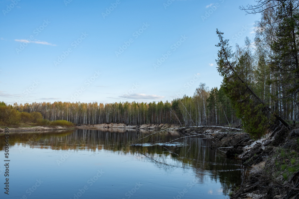 Spring landscape with river and forest at sunset. Beautiful Russian river in spring at golden hour. A turn of the river with picturesque banks.