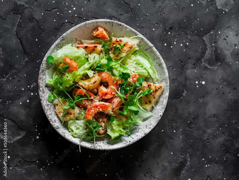 Caesar salad with grilled shrimp on a dark background, top view Caesar salad with grilled shrimp on a dark background, top view