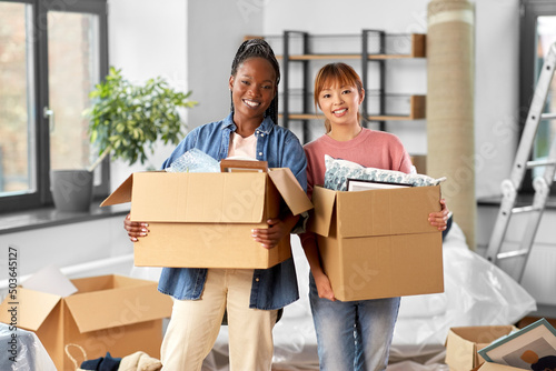moving, people and real estate concept - happy smiling women with boxes at new home © Syda Productions