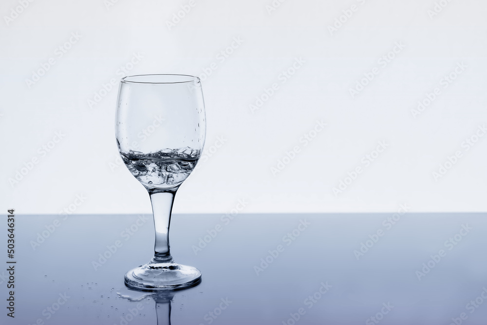 Obraz premium Wine glass with water and drops on the table, copy space