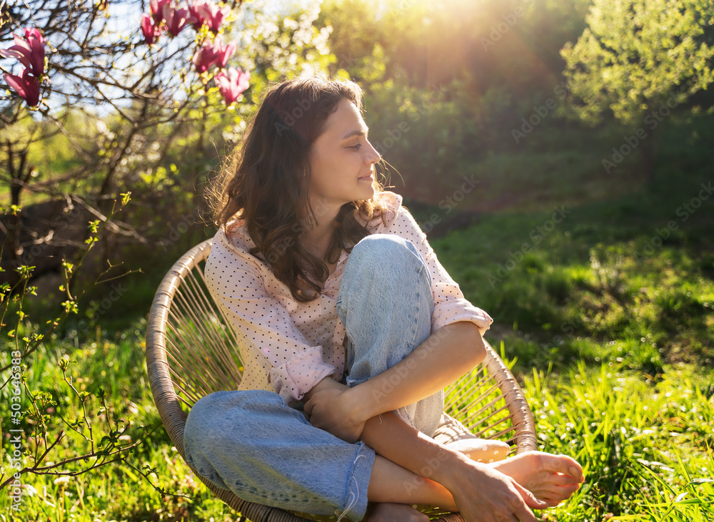 Summer portrait, happy young woman with beautiful smile enjoying nature in garden sitting on chair
