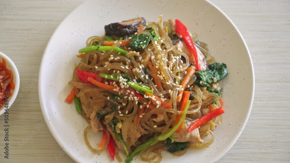 japchae or stir-fried Korean vermicelli noodles with vegetables and pork topped with white sesame - Korean traditional food style japchae or stir-fried Korean vermicelli noodles with vegetables and pork topped with white sesame - Korean traditional food style