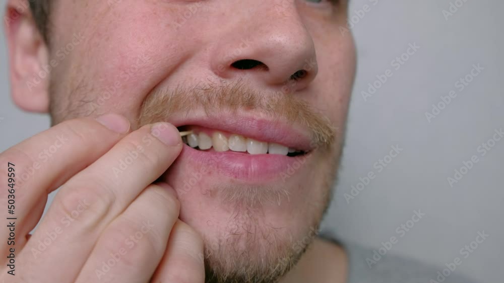 Using Toothpick. Etiquette and Good Manners. Close Up. A young man takes out the remnants of food stuck in his teeth with a toothpick close-up Using Toothpick. Etiquette and Good Manners. Close Up. A young man takes out the remnants of food stuck in his teeth with a toothpick close-up