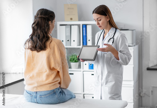 medicine  healthcare and people concept - smiling female doctor showing tablet pc computer to woman patient at hospital