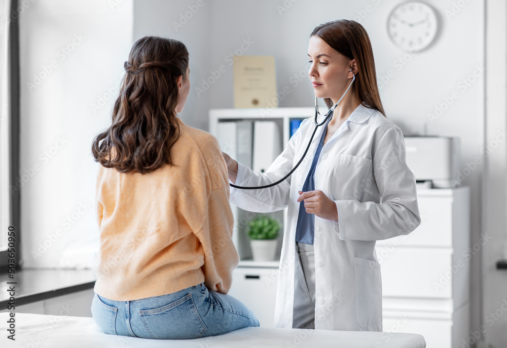 © Syda Productions - medicine, healthcare and people concept - female doctor with stethoscope listening to woman patient at hospital