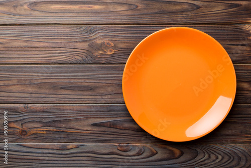 Top view of empty orange plate on wooden background. Empty space for your design