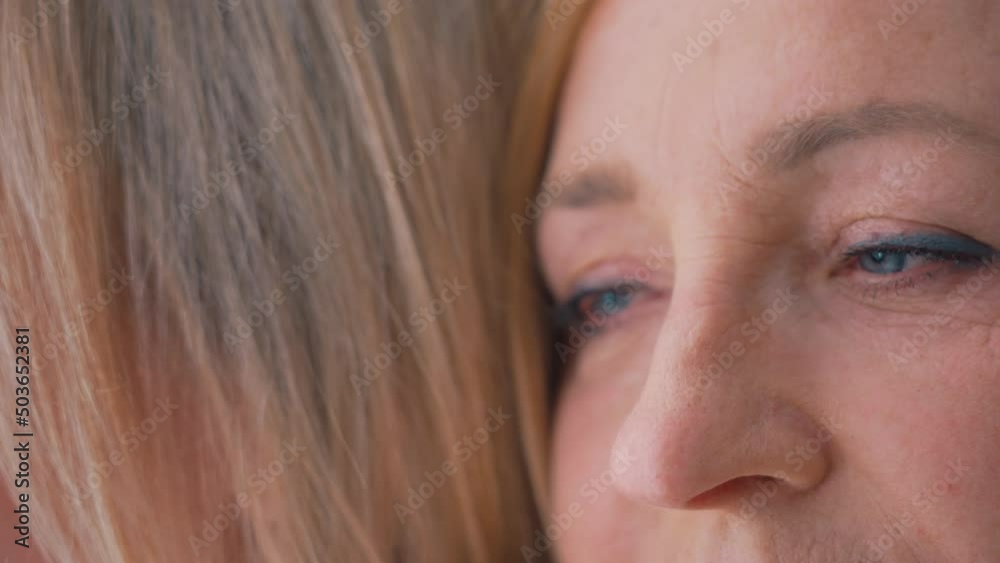 Close-up shot of a middle-aged caucasian wrinkled woman, looking away, closing her eyes, wearing makeup, blue eyeshadow, pink lipstick, leaning her head towards an unrecognizable person. High quality Close-up shot of a middle-aged caucasian wrinkled woman, looking away, closing her eyes, wearing makeup, blue eyeshadow, pink lipstick, leaning her head towards an unrecognizable person. High quality