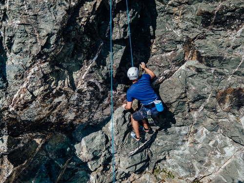 Close up of a man, rock climbing, using help from a rope.