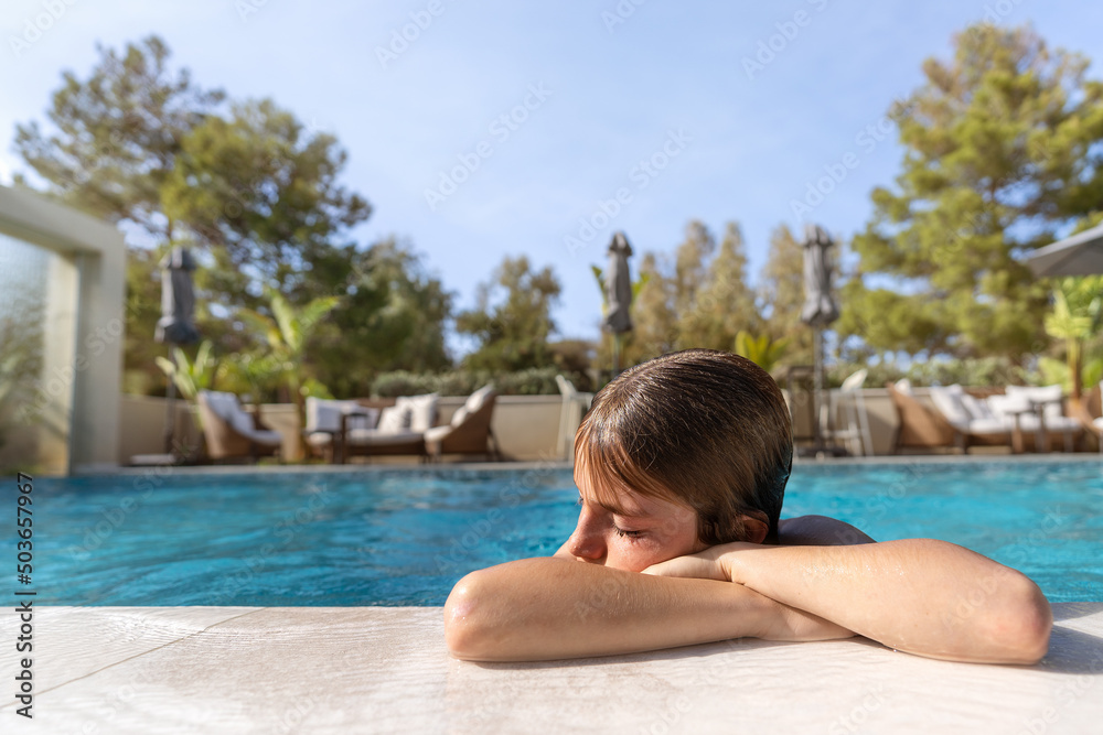 Cute 11 year old boy having a good time in the pool on a summer day