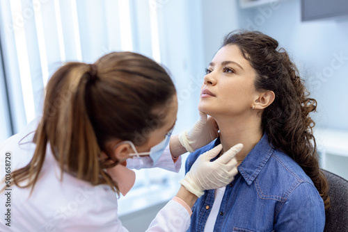 medicine, healthcare and medical exam concept - doctor or nurse checking patient's tonsils at hospital. Endocrinologist examining throat of young woman in clinic photo