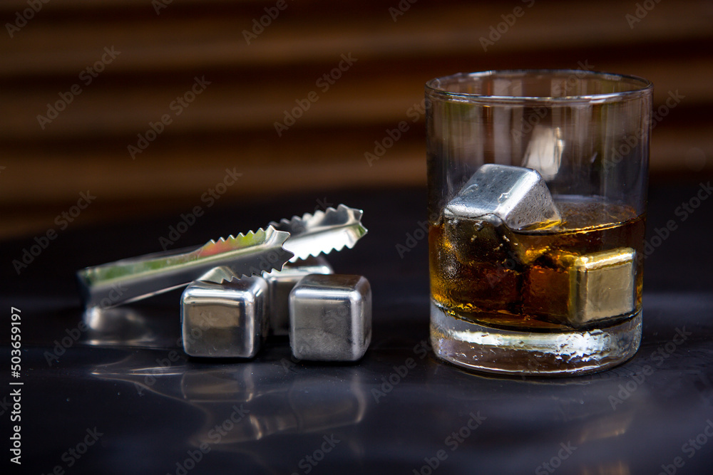 Glass of whiskey eith metal ice cubes Glass of whiskey eith metal ice cubes