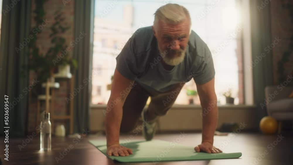 Strong Athletic Fit Senior Man Doing Mountain Climber Exercises During Morning Workout at Home in Sunny Apartment. Concept of Healthy Lifestyle, Fitness, Recreation, Wellbeing and Retirement. Strong Athletic Fit Senior Man Doing Mountain Climber Exercises During Morning Workout at Home in Sunny Apartment. Concept of Healthy Lifestyle, Fitness, Recreation, Wellbeing and Retirement.