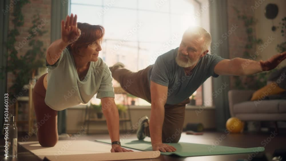 Happy Middle Aged Couple Doing Gymnastics and Yoga Stretching Exercises Together at Home on Sunny Morning. Concept of Healthy Lifestyle, Fitness, Recreation, Couple Goals, Wellbeing and Retirement. Happy Middle Aged Couple Doing Gymnastics and Yoga Stretching Exercises Together at Home on Sunny Morning. Concept of Healthy Lifestyle, Fitness, Recreation, Couple Goals, Wellbeing and Retirement.