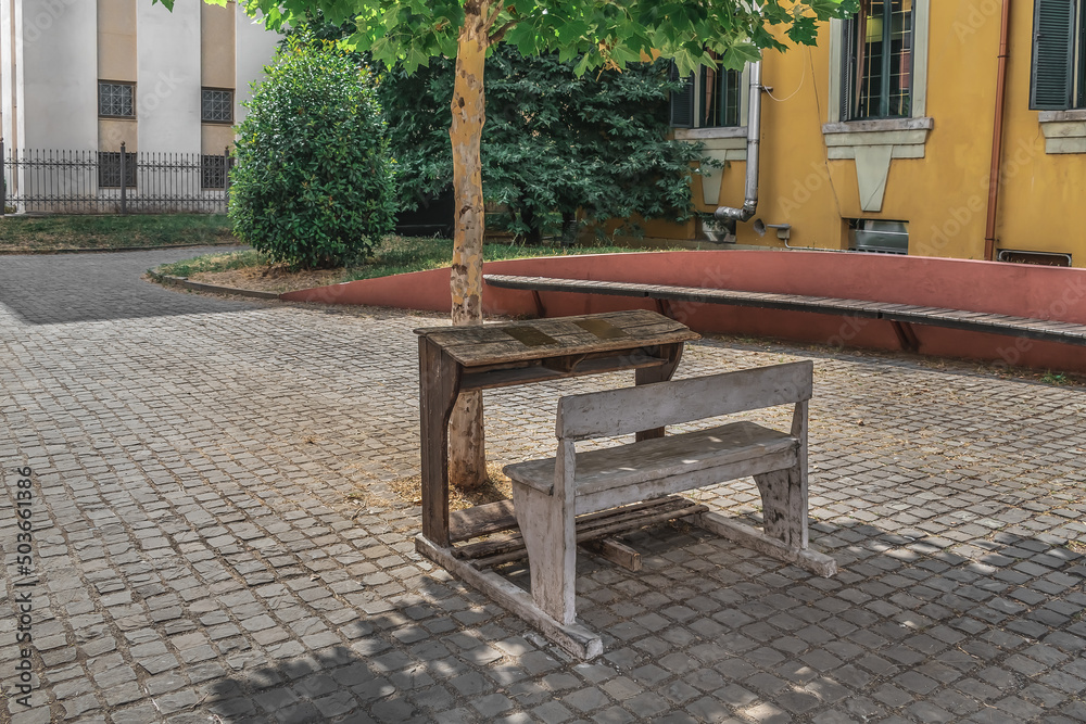 Obraz na płótnie An old school desk on a city street in Tirana, Albania. Wooden table and bench under a tree outdoors w salonie