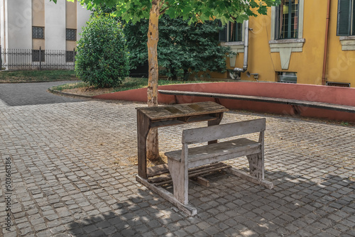 An old school desk on a city street in Tirana, Albania. Wooden table and bench under a tree outdoors