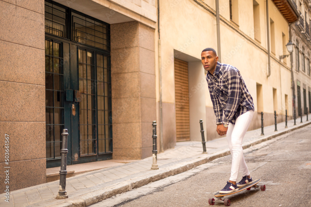 young black man rollerblading with long board on the street.