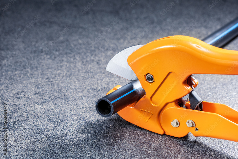 Plumber cuts the plastic pipe using a cutter. Repair water system concept. Plumber cuts the plastic pipe using a cutter. Repair water system concept.