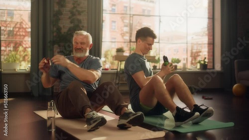 Middle Aged Man Exercising at Home with Personal Trainer. Senior Male Strengthening Core Muscles with Kettlebell Workout. Young Man or Grandchild Supporting and Training with Elderly Man. photo