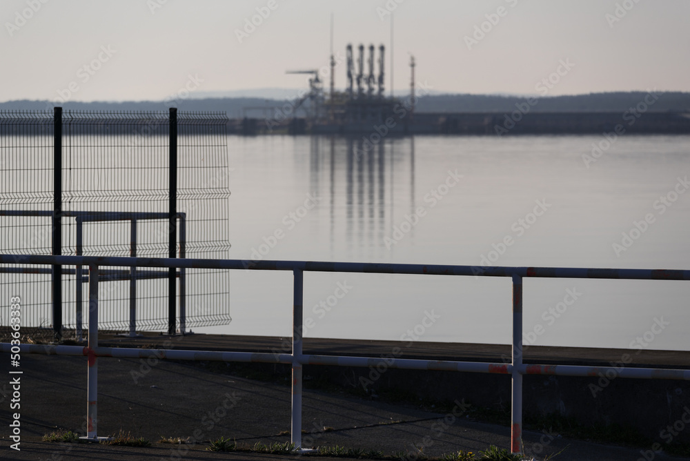 SEAPORT - Fences on breakwater with LNG terminal in the background
