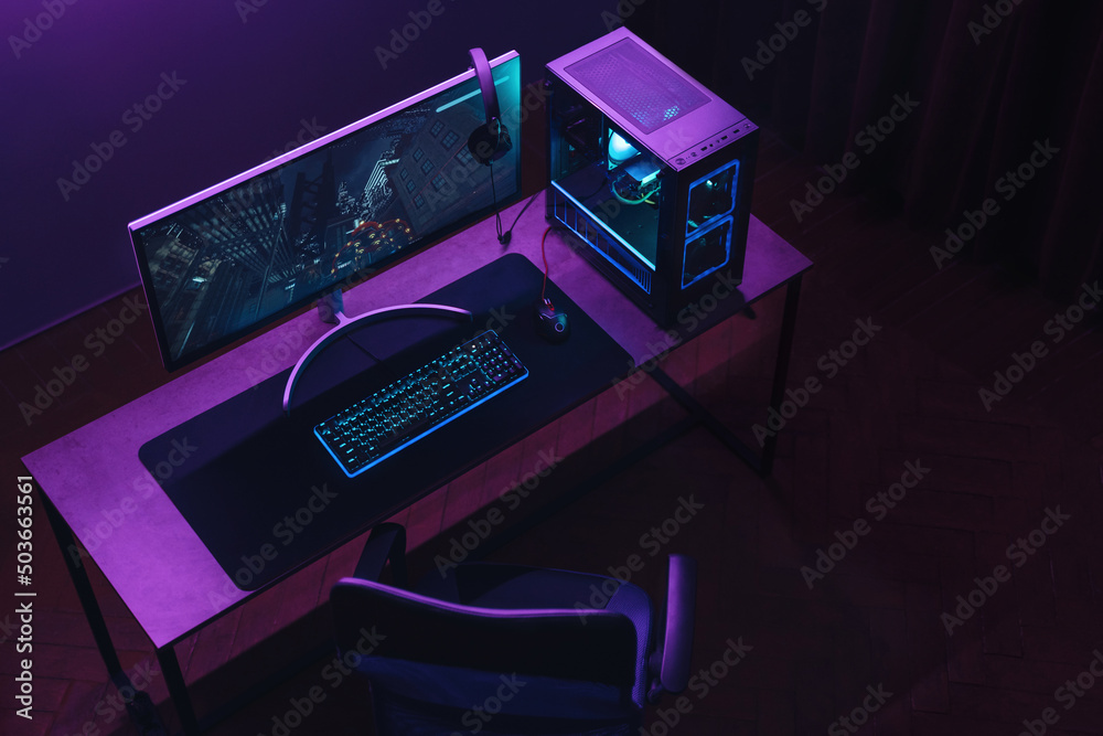 Top view of gamer work space and professional gaming setup: mouse,  keyboard, monitor, headset, powerful computer. Premium PC with RGB light  inside. Cyber sportsman empty studio with streaming setup Stock Photo