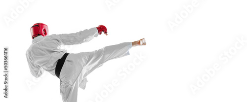 Back view. Portrait of young sportive man wearing white dobok, helmet and gloves practicing isolated over white background. Concept of sport, workout, health.
