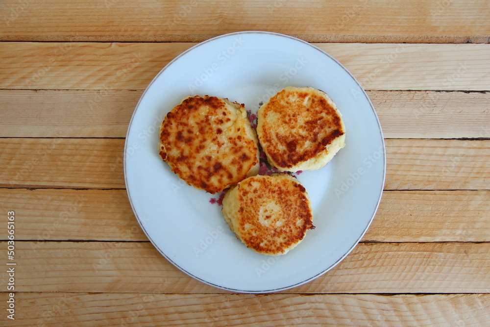 Homemade cheesecakes on a plate on the wooden background, top view Homemade cheesecakes on a plate on the wooden background, top view