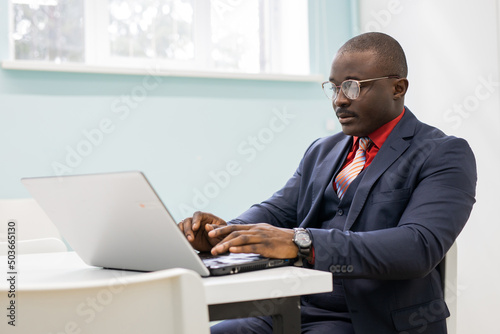 successful african businessman working on laptop in office