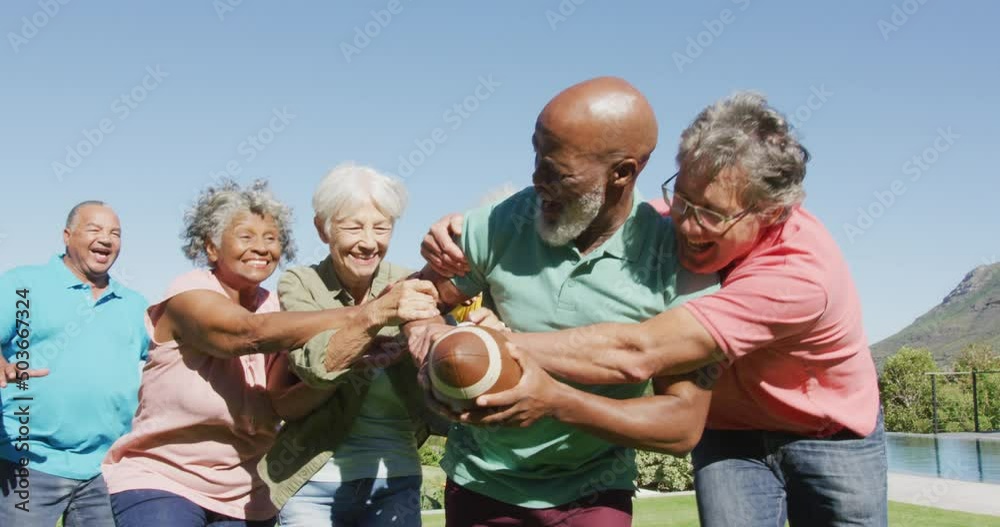 Happy senior diverse people playing rugby in garden at retirement home
