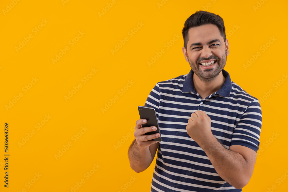 Portrait of happy young man cheering with raising his fist Portrait of happy young man cheering with raising his fist