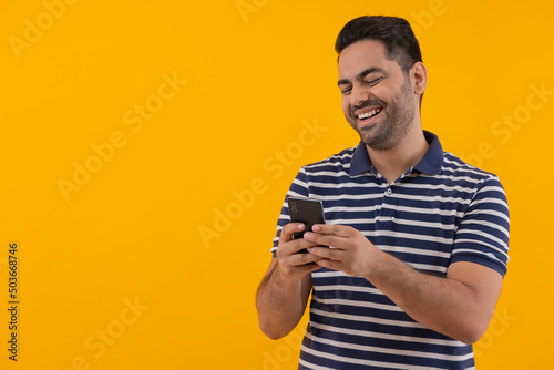 Portrait of happy young man having fun while using Smartphone