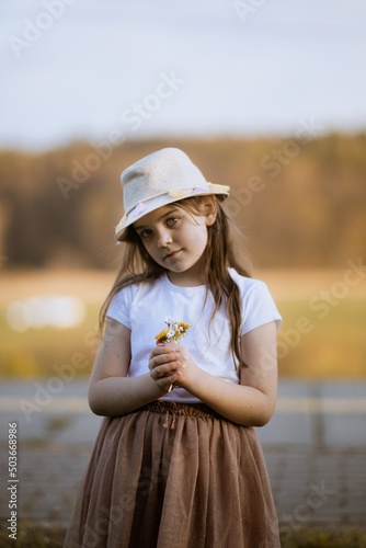 Dziewczynka trzyma w dłoni bukiet kwiatów
