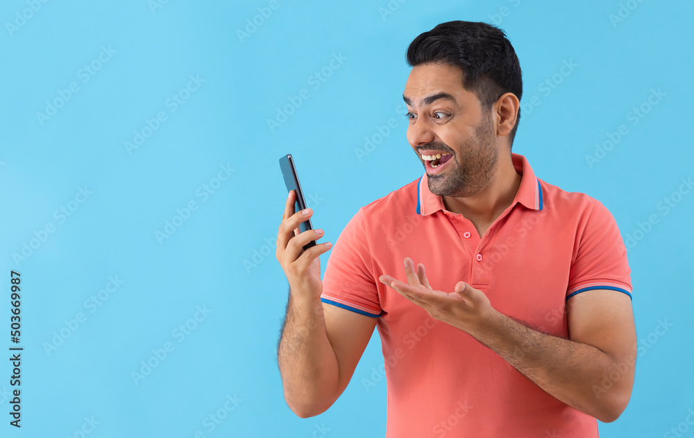 Portrait of a cheerful young man looking at Smartphone holding his hand Portrait of a cheerful young man looking at Smartphone holding his hand