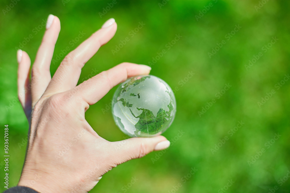 Human hand hold glass Earth globe on green grass background, Saving environment concept. Human hand hold glass Earth globe on green grass background, Saving environment concept.