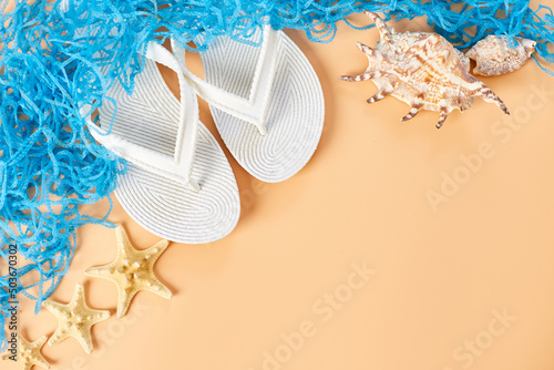 Flat lay summer composition, Tropical palm leaves, white flip flop, seashells on pastel orabge background, Summer vacation concept, top view, copy space