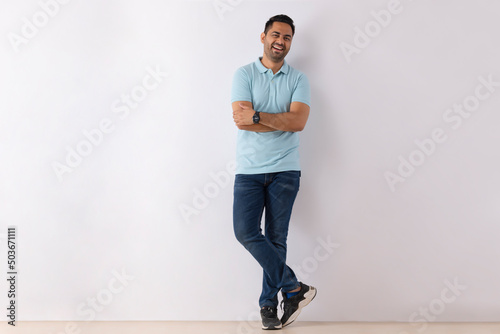 Portrait of a young man standing with hands folded against white background