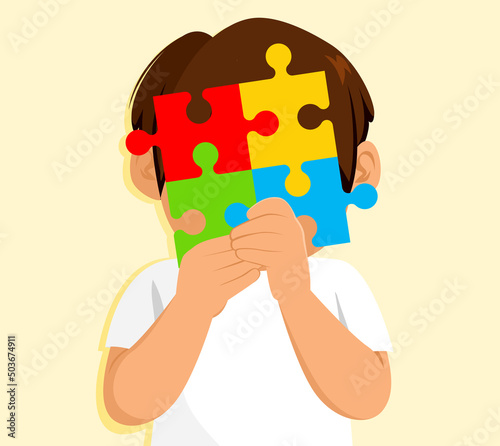 Cute little boy covering his face with big puzzle pieces austism concept. Autism Spectrum Disorder concept.