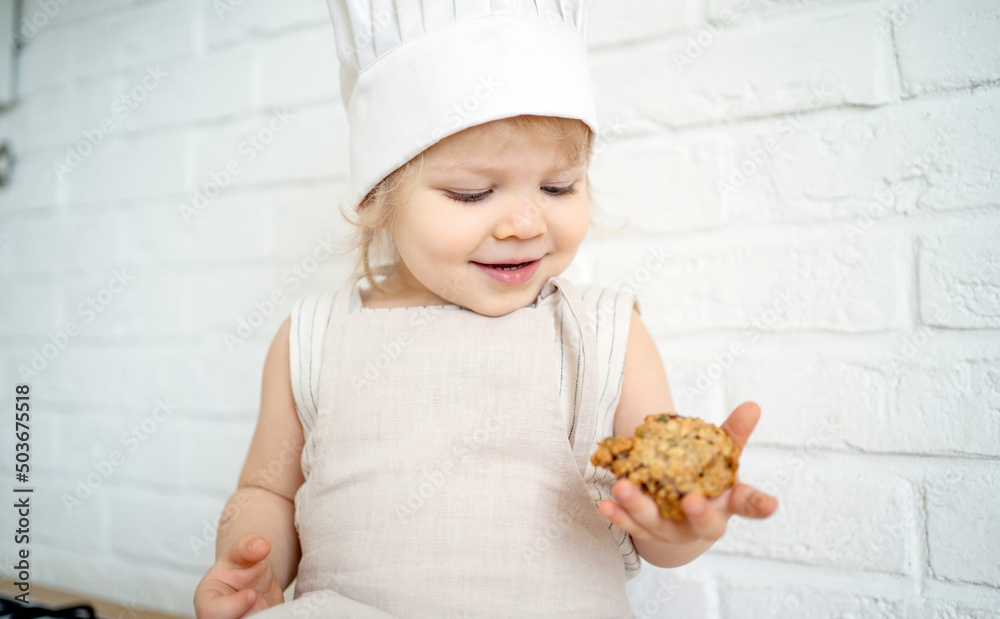 Happy childhood a little girl is playing in the kitchen, cooking cookies for the cook. Happy childhood a little girl is playing in the kitchen, cooking cookies for the cook.