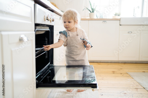 A little girl is playing in the kitchen, a chef's uniform.