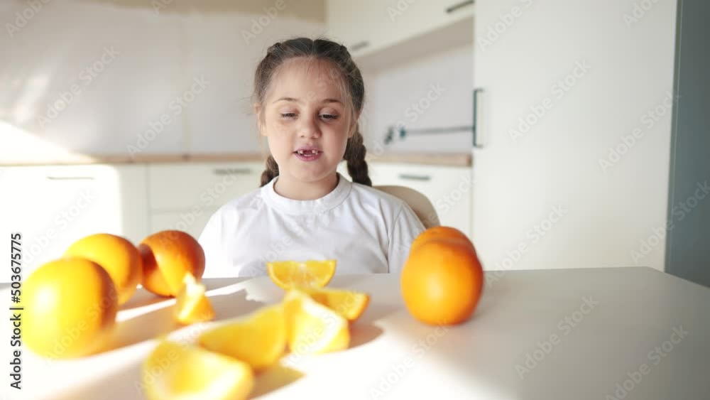 girl child eating oranges. happy family fruit healthy food kid concept. little girl daughter eating oranges at the table in the kitchen indoors. juicy fruits oranges are for a healthy dream diet girl child eating oranges. happy family fruit healthy food kid concept. little girl daughter eating oranges at the table in the kitchen indoors. juicy fruits oranges are for a healthy dream diet