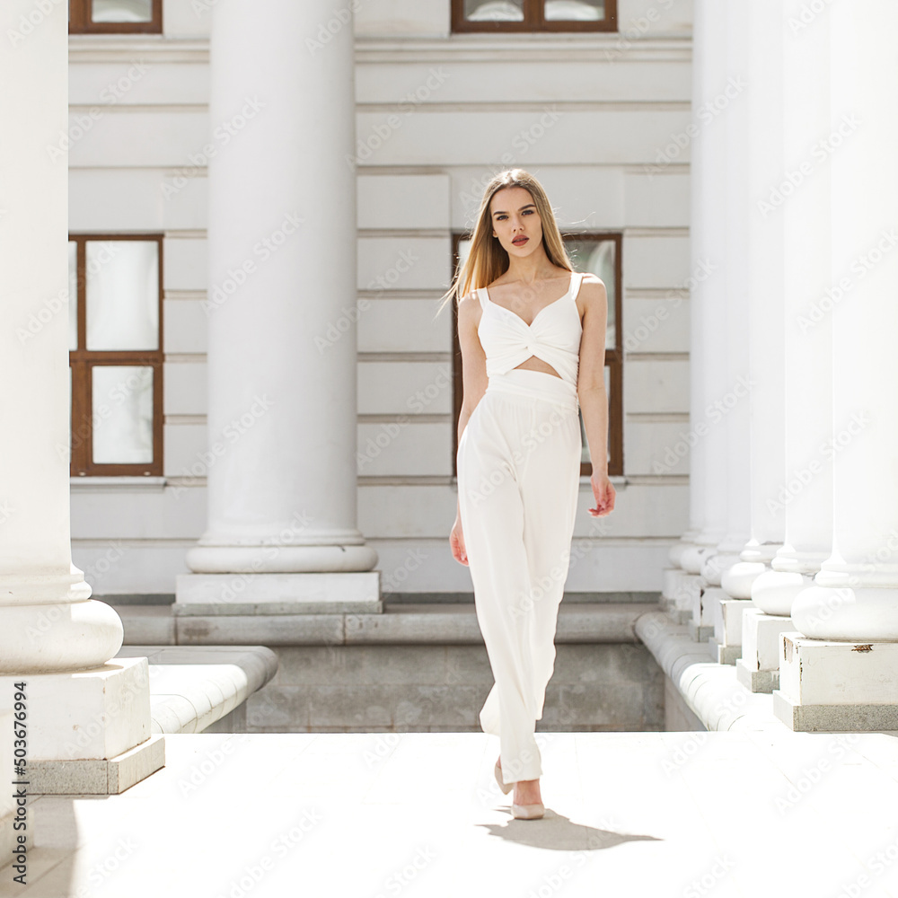 Portrait of a young beautiful blonde model in white trousers