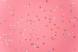Silver stars glittering confetti on pink background. Trendy festive holiday backdrop. Many star-shaped particles for a postcard, invintation or web banner