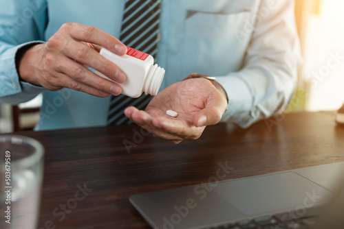 Close up business hand taking medicine pill while working at office.