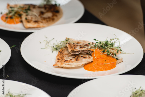 Cheburek traditional balkan meat pastry pie with herbs on a white plate. Served with sauce and micro green