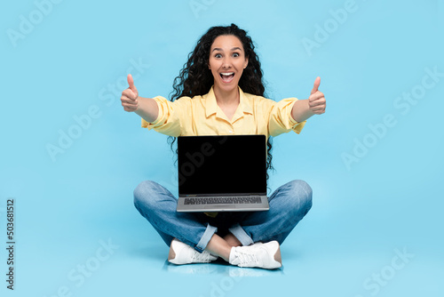 Happy woman showing black empty laptop screen gesturing like © Prostock-studio